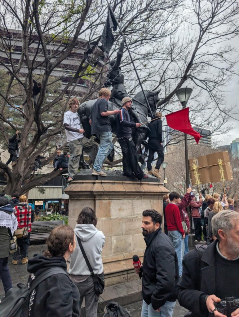 Students climbed the bronze statue of Jeanne d'Arc and waved red communist flags at the anti-Pauline Hanson rally in Melbourne on August 13. Picture: Josh Spasaro.
