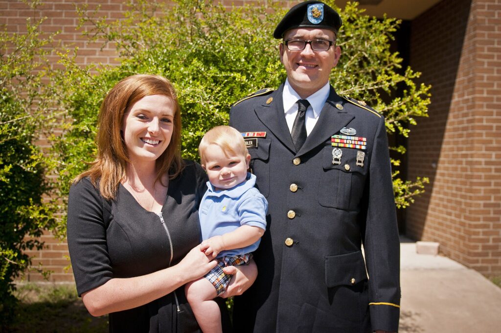 Staff Sgt. Patrick Zeigler, his wife, Jessica, and their son, Liam, enjoy a moment in the sun together outside Fort Hood's Survivor Outreach Services building while waiting for the verdict in the court martial of Maj. Nidal Hasan, who was accused of carrying out the Nov. 5, 2009 shooting rampage that killed 13 and wounded 32, Aug. 26, 2009. Zeigler was getting cleared to attend officer candidate school when he was shot four times in the incident, including once in the head which necessitated the removal of 20 percent of his brain. Hasan was found guilty less than an hour after this photo was taken, and sentenced to death two days later. (U.S. Army photo by Sgt. Ken Scar, 7th Mobile Public Affairs Detachment)